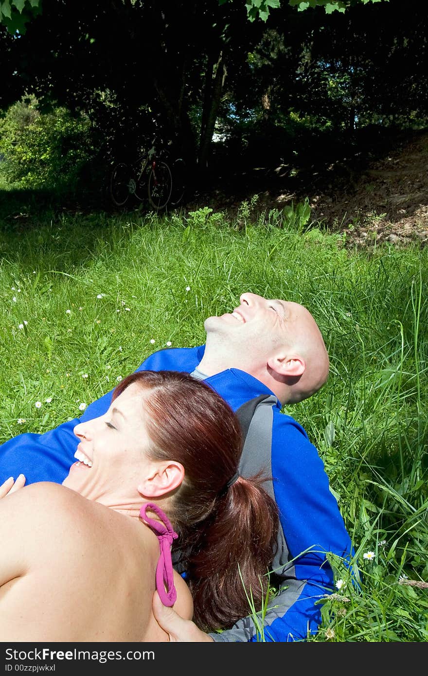 Happy couple sit on the grass and laugh in the park. Vertically framed photograph. Happy couple sit on the grass and laugh in the park. Vertically framed photograph