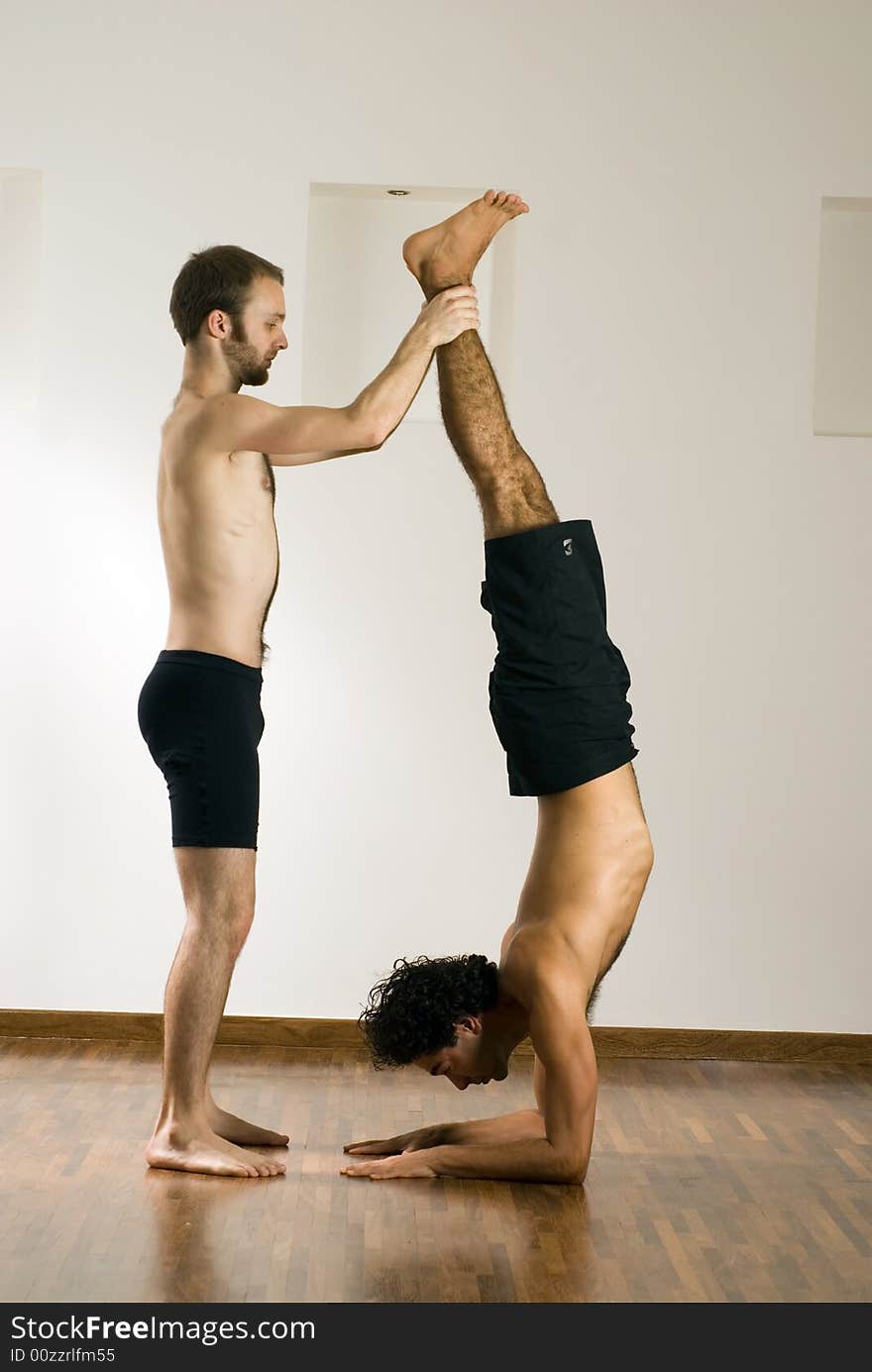 One man is balancing another man by holding his feet. Vertically framed photograph. One man is balancing another man by holding his feet. Vertically framed photograph