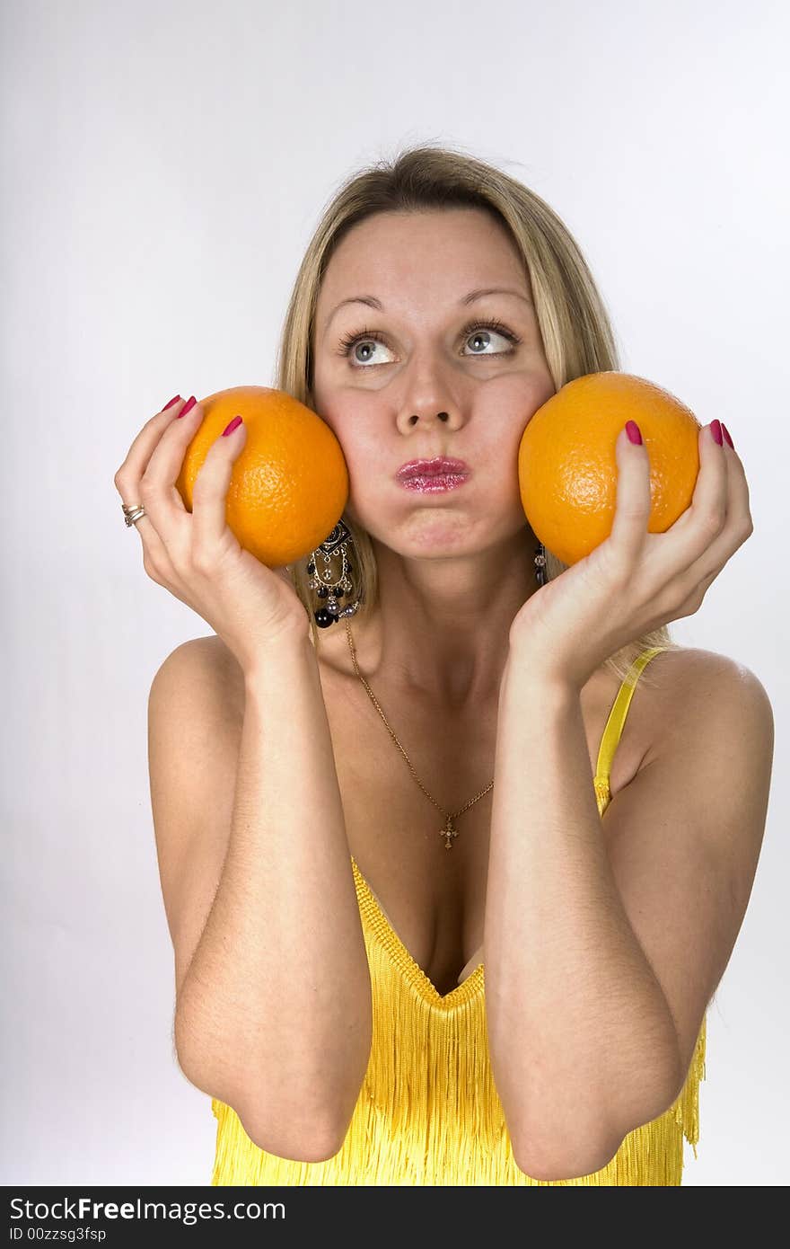 Blonde woman in yellow dress with two oranges in her hands. Blonde woman in yellow dress with two oranges in her hands