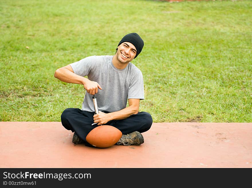 Man in Park Pumping Air into Football - Horizontal