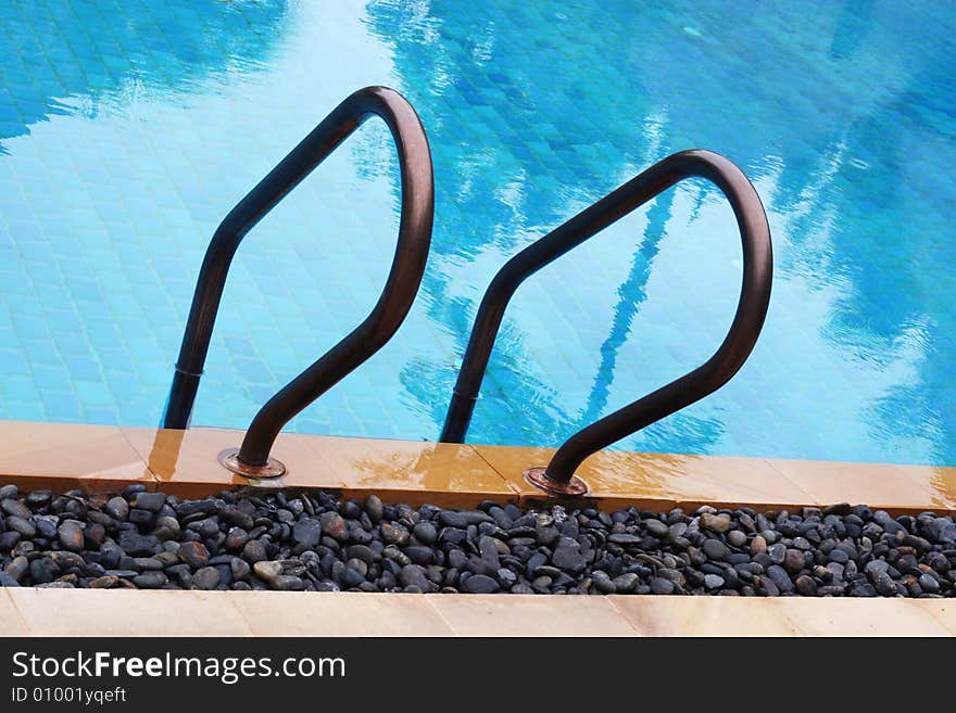 Close-up of railing and steps of a swimming pool. Close-up of railing and steps of a swimming pool.