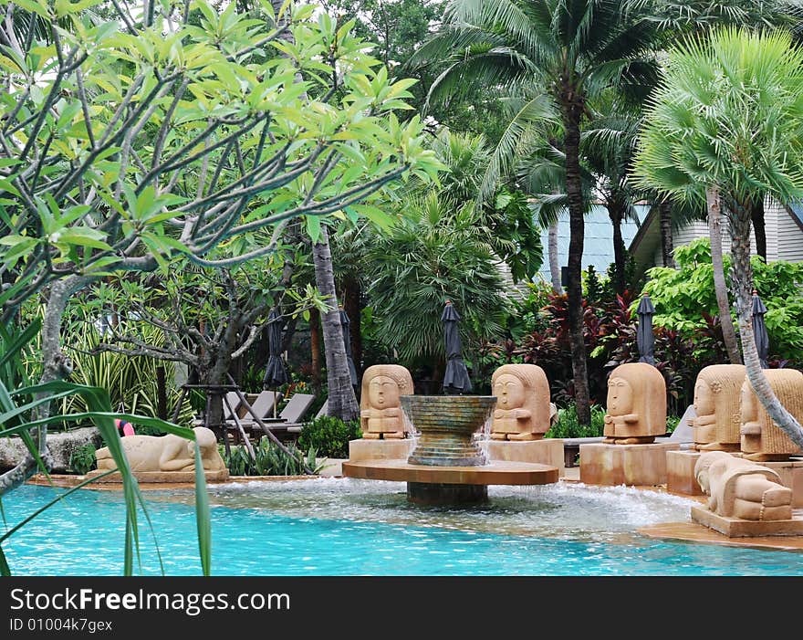 Asian statues overlooking a swimming pool at a resort in Thailand - travel and tourism.