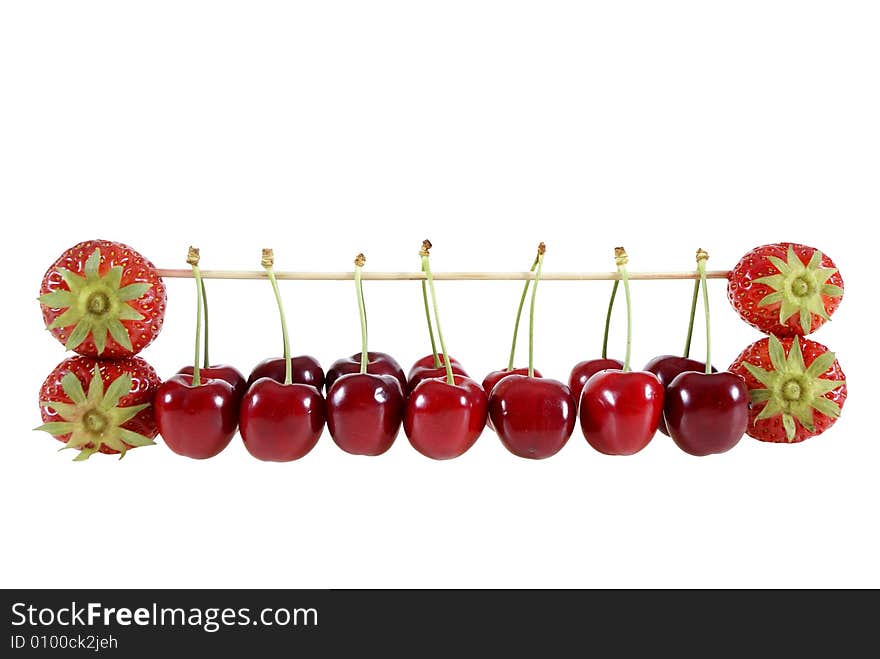 Strawberries and cherries suspended on a stick isolated on the white background. Strawberries and cherries suspended on a stick isolated on the white background