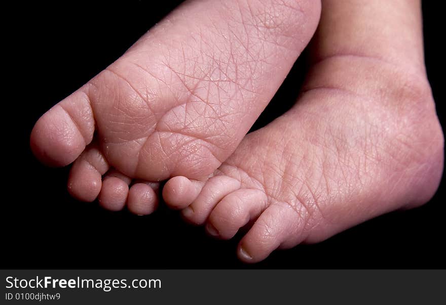 Baby feet in front of black background extended to camera