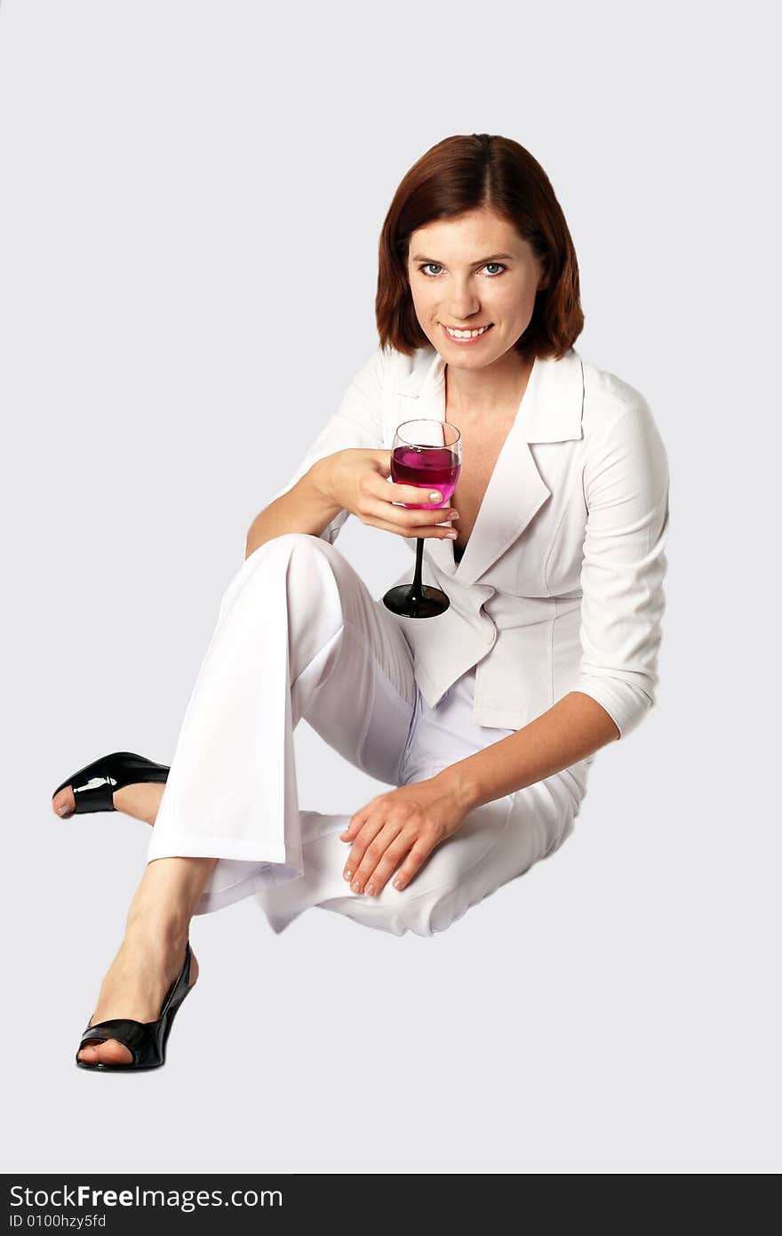 Business the woman in white clothes holds in a hand a glass with a bright drink. Business the woman in white clothes holds in a hand a glass with a bright drink