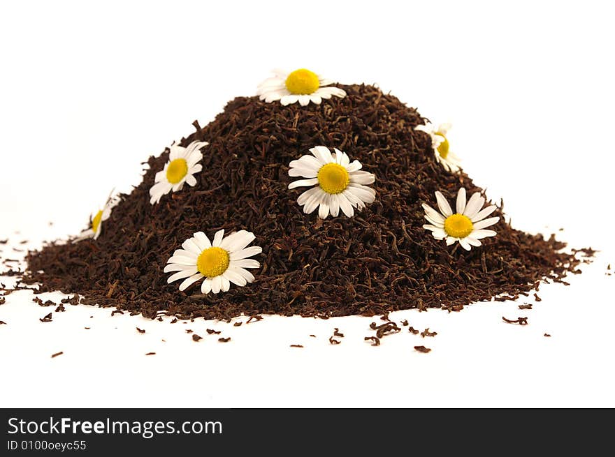 Heap of black tea and chamomile blossoms isolated on white