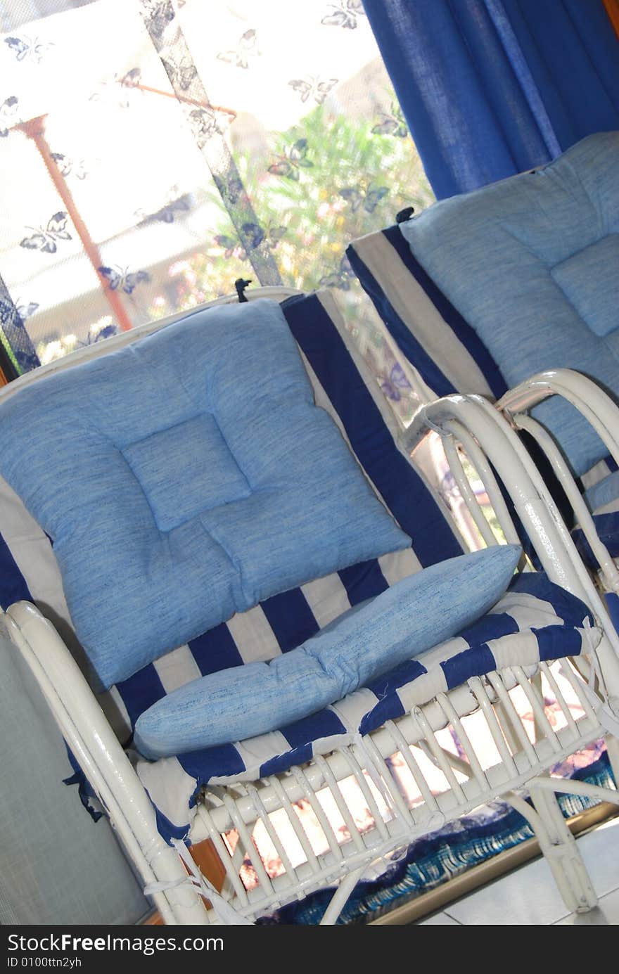 Two white wood patio chairs with blue and white cushions