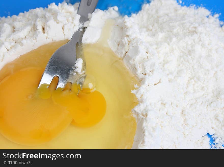 Raw egg and flower with a fork in the yolk. Raw egg and flower with a fork in the yolk