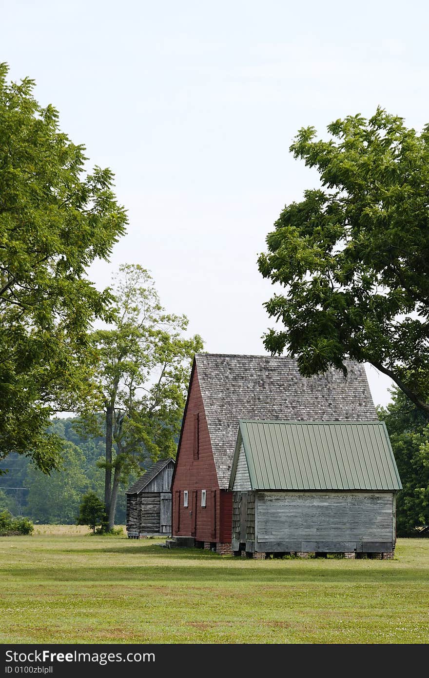 Old red wooden barn and two outbuildings in a wooded field. Old red wooden barn and two outbuildings in a wooded field.