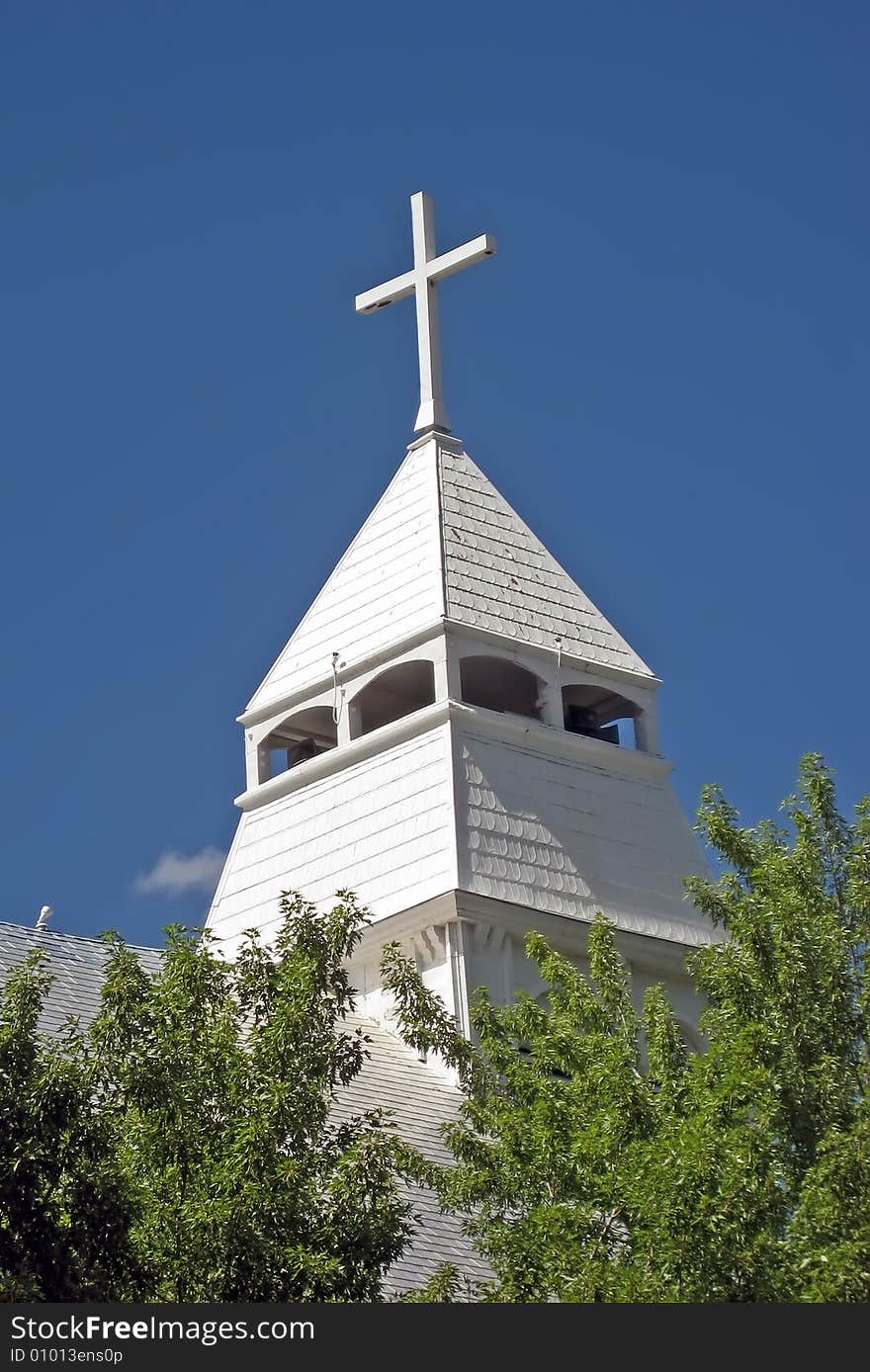 White church steeple with cross against blue sky. White church steeple with cross against blue sky.