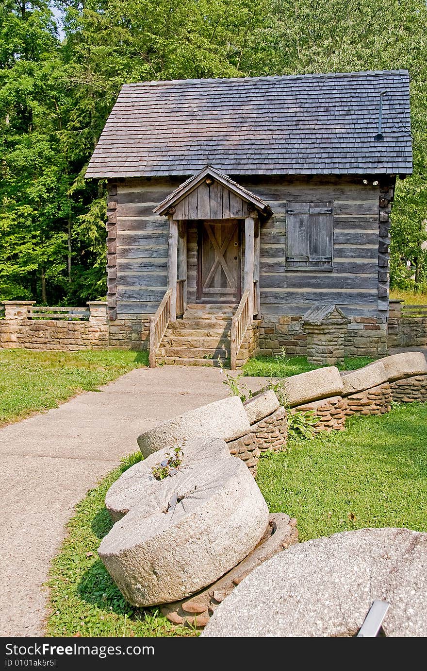 An old weathered mill with old mill wheels lining the path up to the door