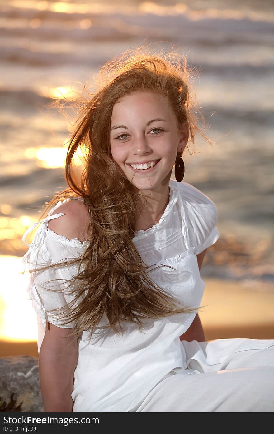 Beautiful young girl relaxing on the beach at sunset