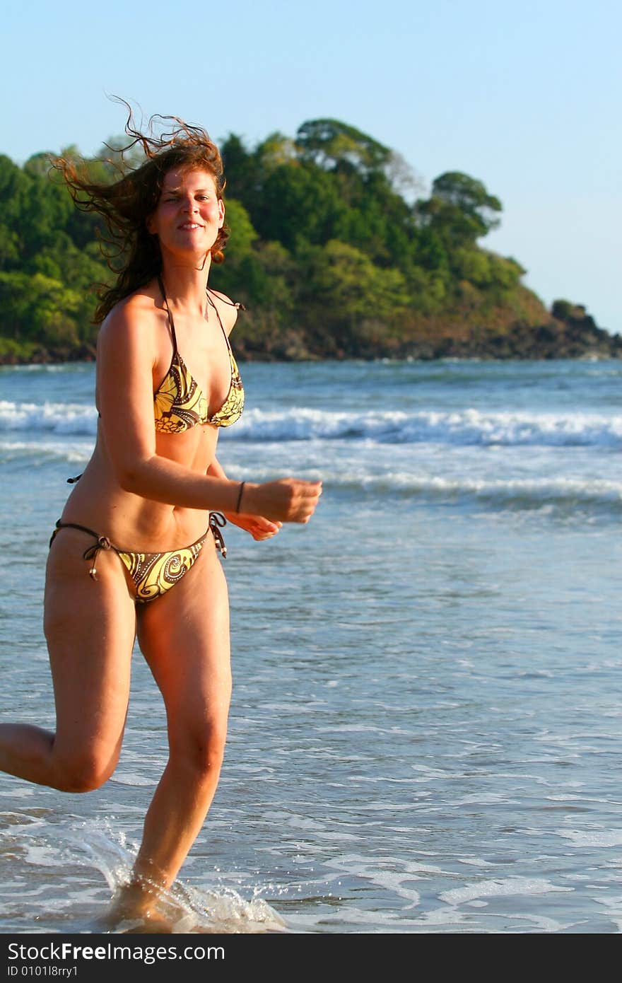 A young woman at the beach in the water. Running in the water with a bikini. Ideal vacation shot. A young woman at the beach in the water. Running in the water with a bikini. Ideal vacation shot.