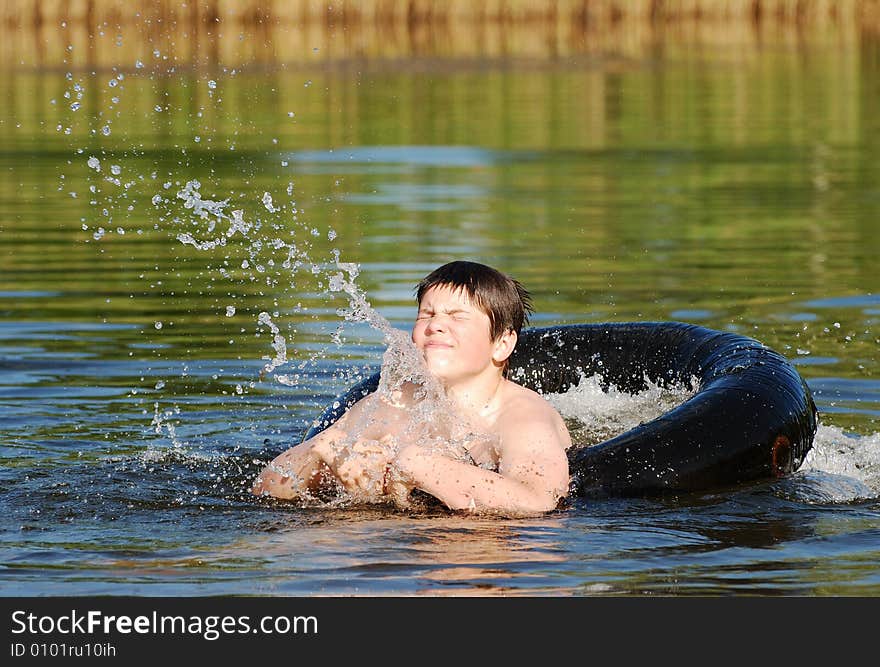 The boy in a tube making splashes ina small lake late afternoon (Lithuania).