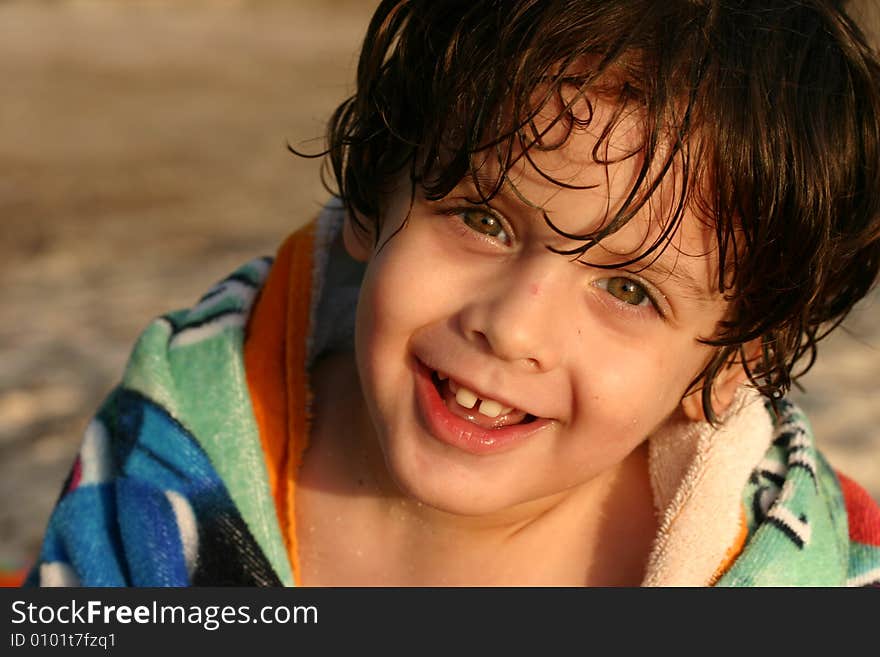 A kid at the beach smiles. A kid at the beach smiles.