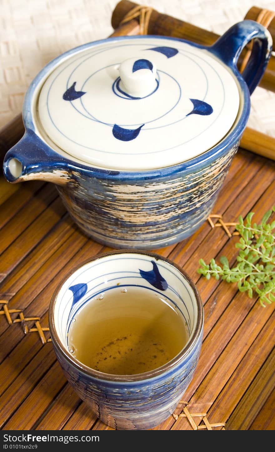 Close up of a cup of green tea and teapot on a bamboo tea tray. Focus on the tea. Close up of a cup of green tea and teapot on a bamboo tea tray. Focus on the tea.