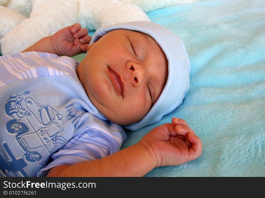 Week old baby boy on a blue blanket early in the morning. Week old baby boy on a blue blanket early in the morning