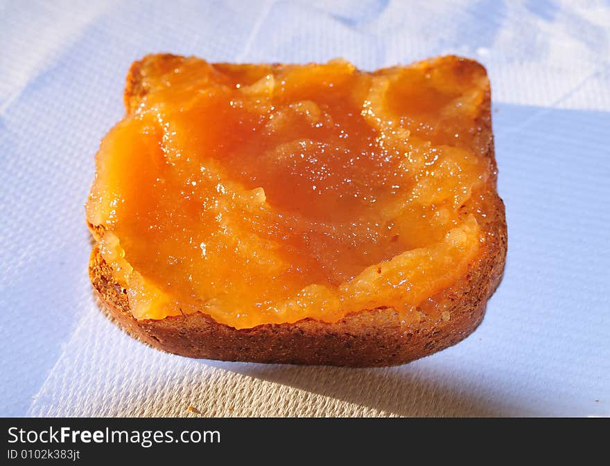 A snack with a rusk biscuit covered with apple jam. Natural sunset light plus flash light. Close shot. A snack with a rusk biscuit covered with apple jam. Natural sunset light plus flash light. Close shot.