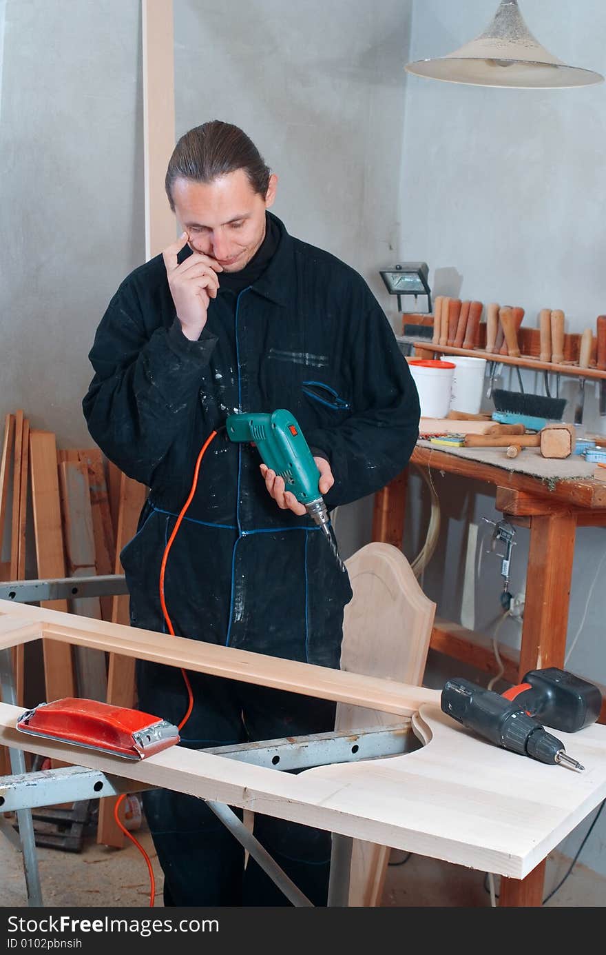 Young carpenter thinking about work in his workshop. Young carpenter thinking about work in his workshop