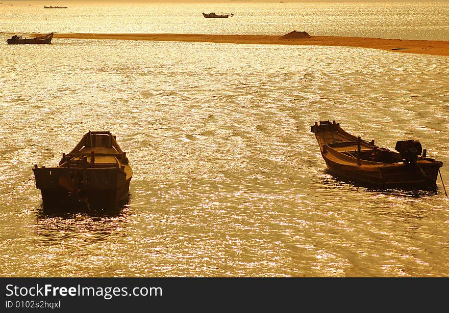 The fishing boat under the setting sun, the golden color sea water, composes a beautiful landscape painting. Photography in the Weihai Shandong China