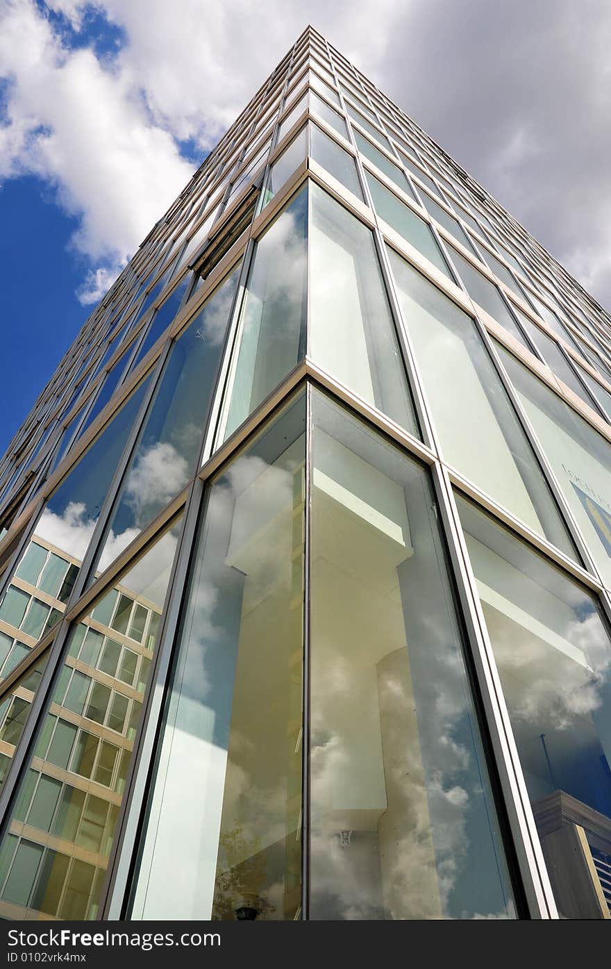 The corner of an office building seen from below and with a blue sky and cloudy sky. The corner of an office building seen from below and with a blue sky and cloudy sky.