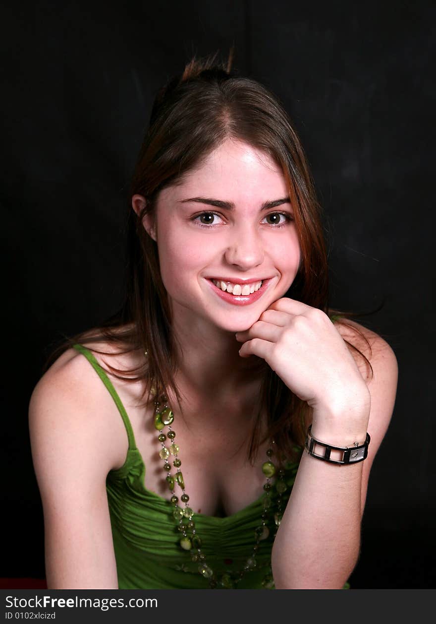 Portrait of a smiling beautiful teenage girl with green beads on her neck against black back-ground. Portrait of a smiling beautiful teenage girl with green beads on her neck against black back-ground.