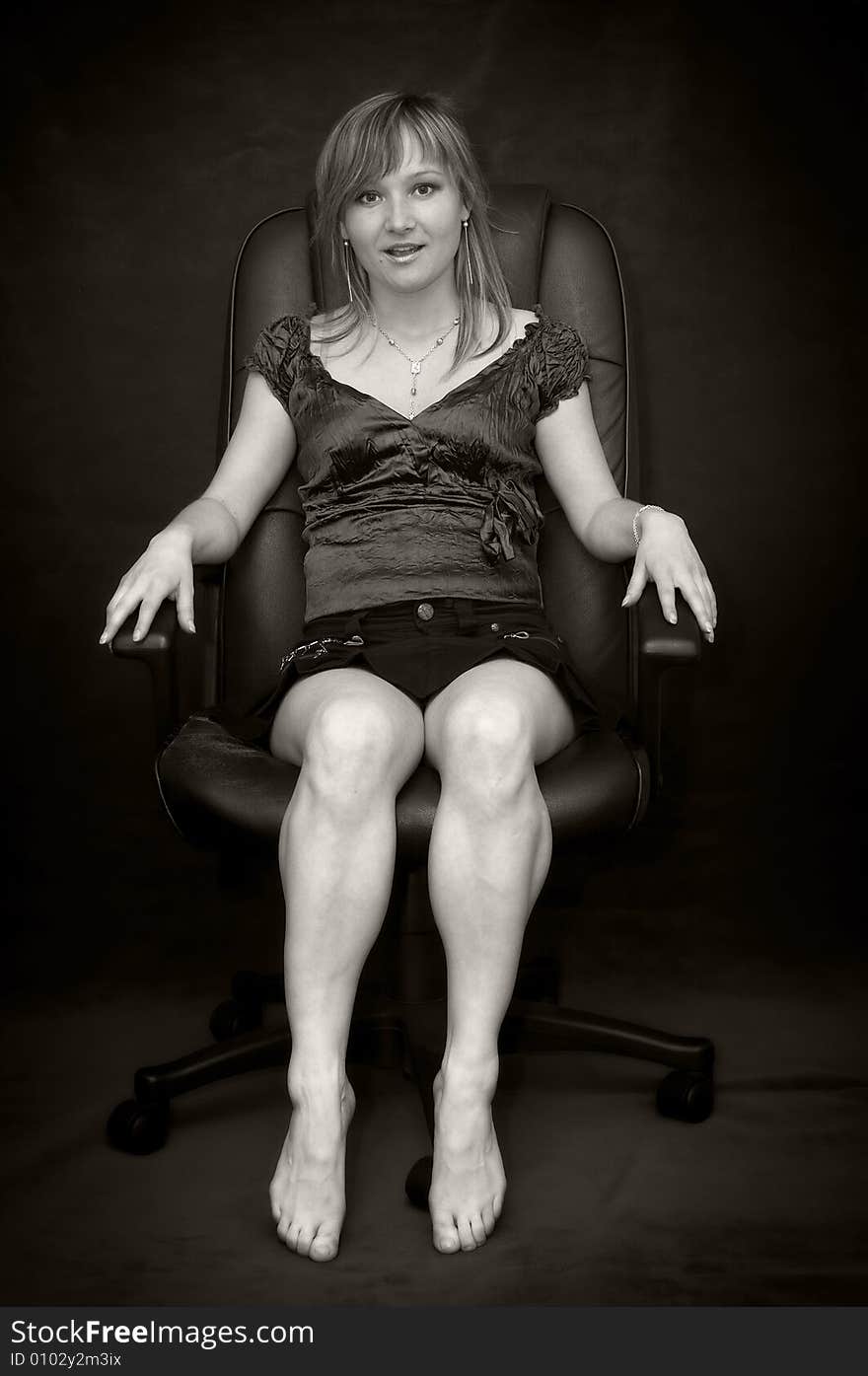 Young woman in black armchair barefooted. Young woman in black armchair barefooted