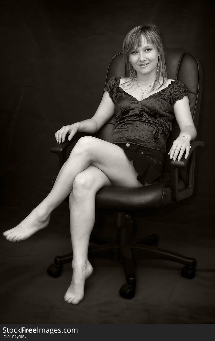 Young woman in black armchair barefooted. Young woman in black armchair barefooted