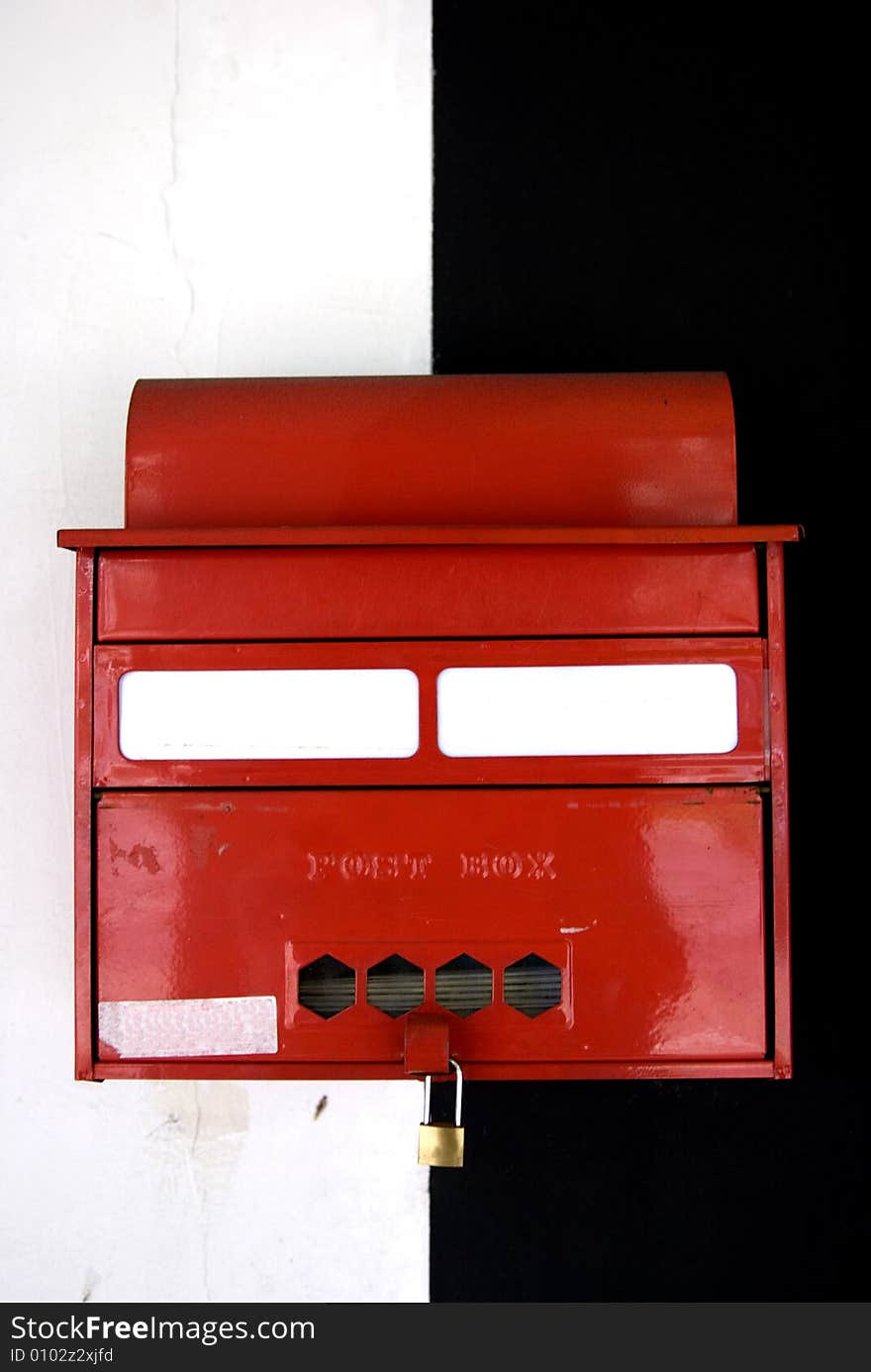 A letter box in front of a black and white wall