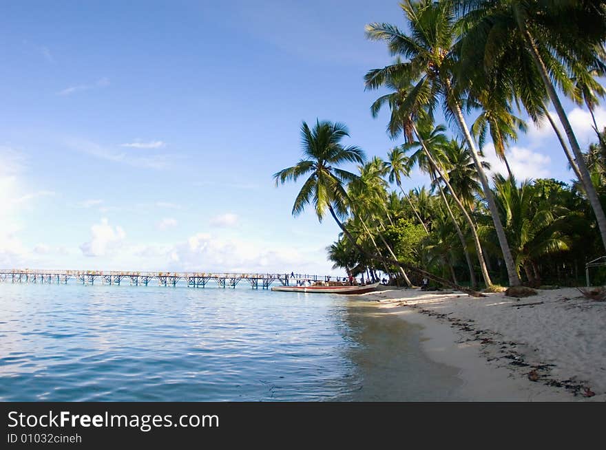 Tropical seascape with palm trees, boat  and bridge an indonesian island.