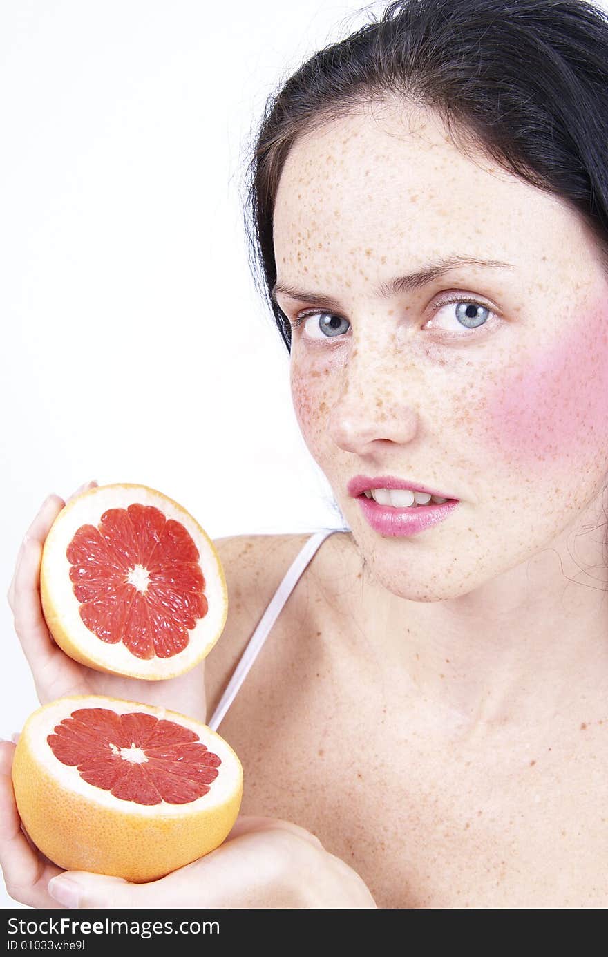 Portrait of a beautiful brunette woman with light grey eyes and freckles on her skin holding a grapefruit. Portrait of a beautiful brunette woman with light grey eyes and freckles on her skin holding a grapefruit