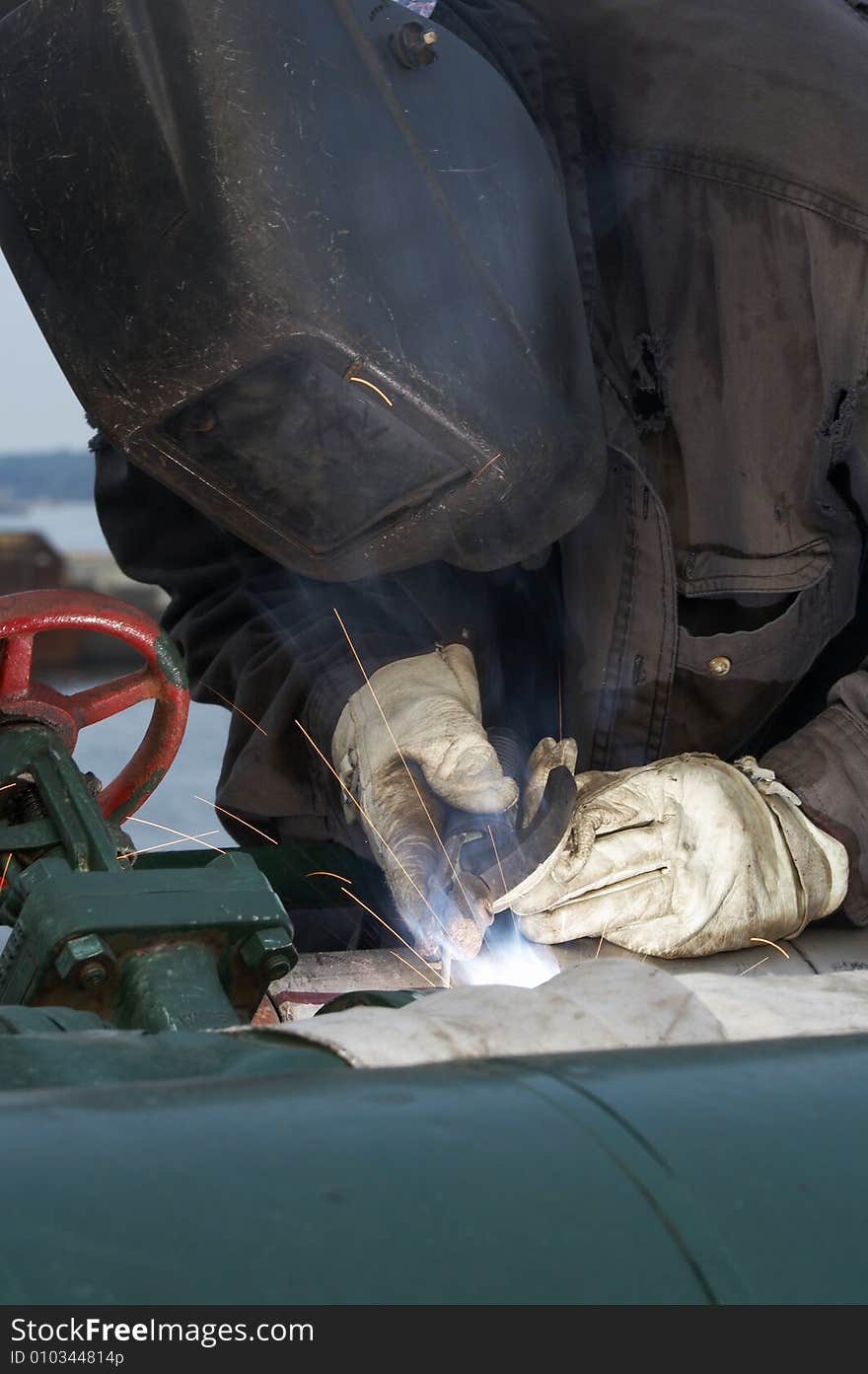 A welder working at shipyard during day shift. A welder working at shipyard during day shift