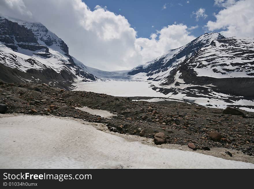 A retreating glacier in a wide valley among the mountain peaks. A retreating glacier in a wide valley among the mountain peaks.