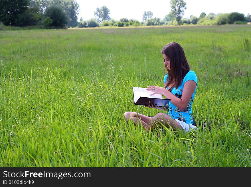 Young woman on the meadow in the summer reading a book. Young woman on the meadow in the summer reading a book.