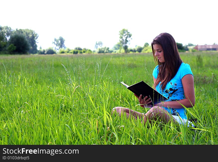 Young woman on the meadow in the summer reading a book. Young woman on the meadow in the summer reading a book.