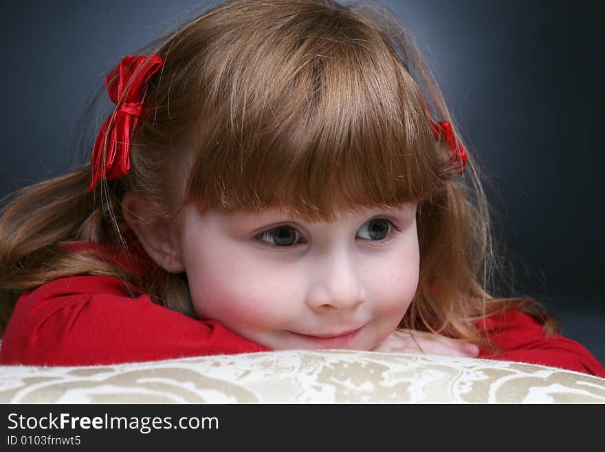 Pretty little girl in red peeking over the arm of a white couch. Pretty little girl in red peeking over the arm of a white couch