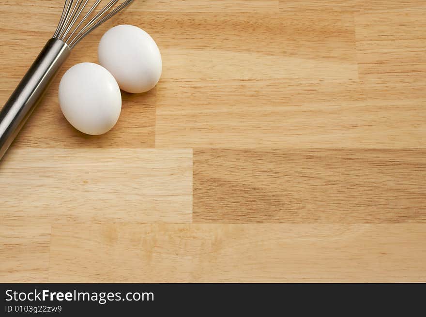 Whisk and Eggs on a wooden background. Room for your own text.