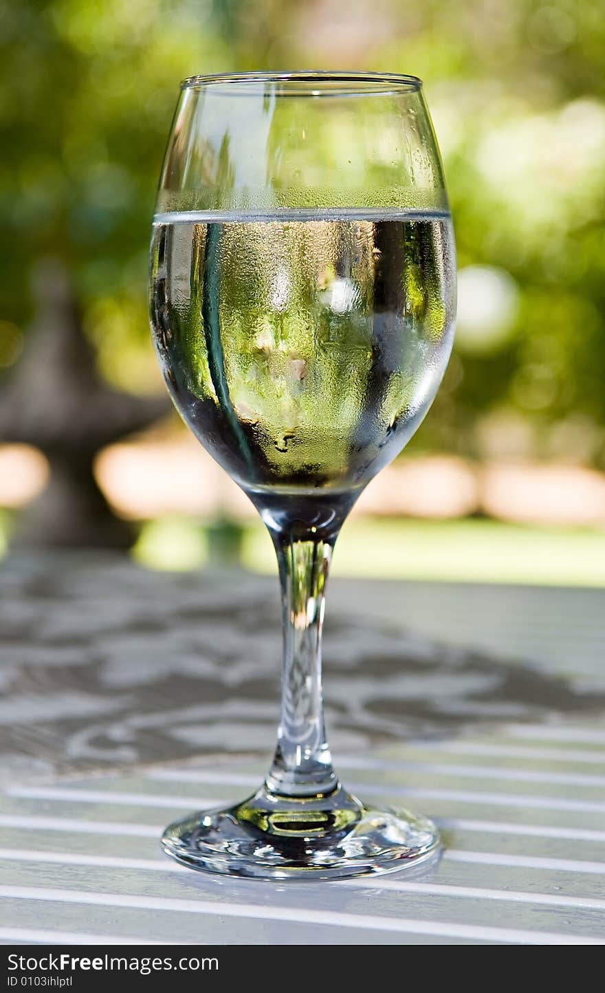 Glass of cold water on garden table in hot summer