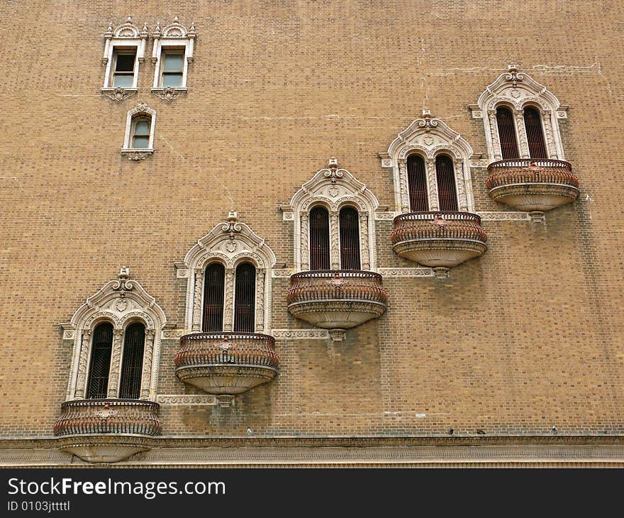 Strangely decorated windows forming a diagonal pattern on a large empty brick wall. Strangely decorated windows forming a diagonal pattern on a large empty brick wall