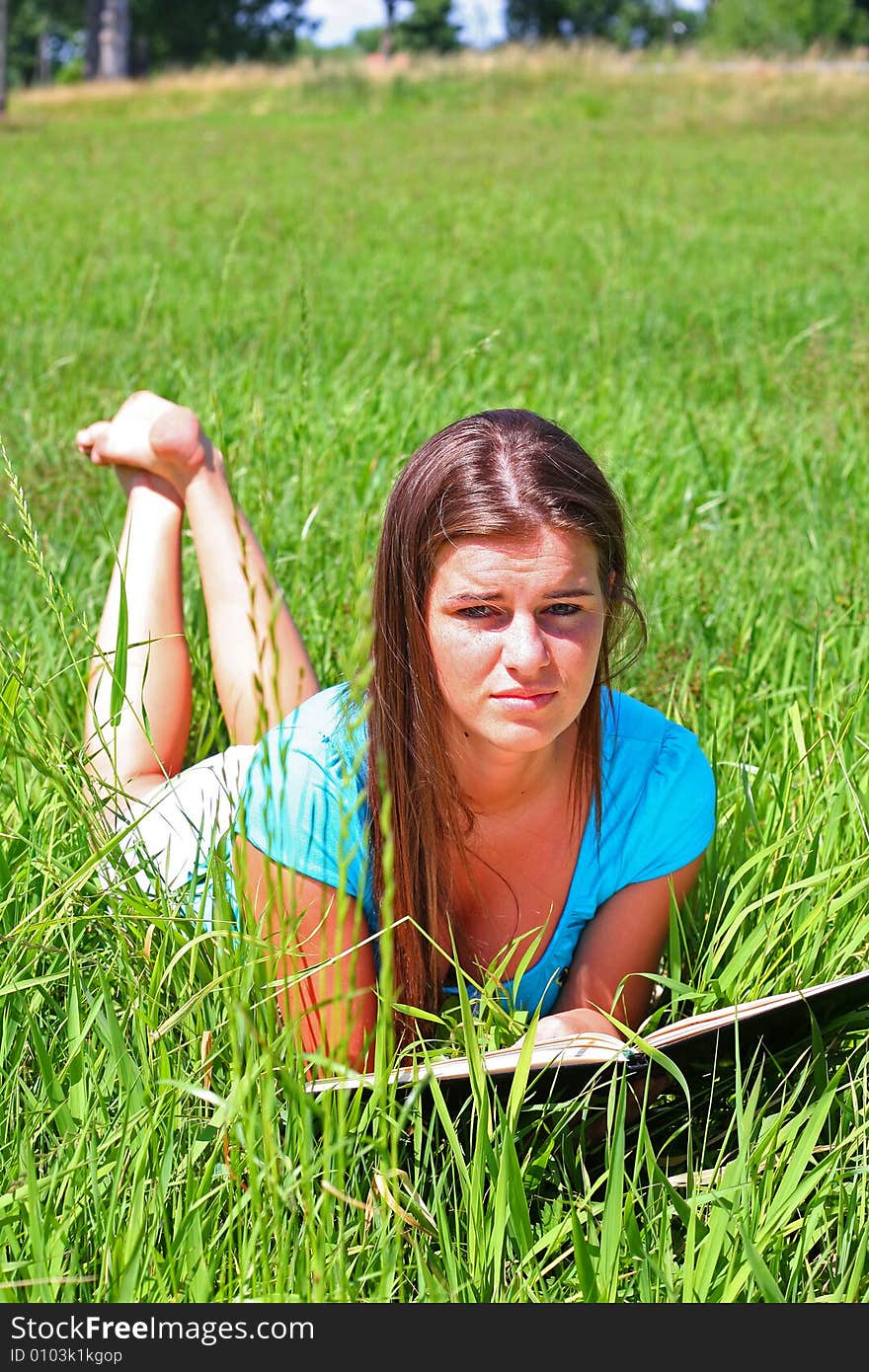 Young woman on the meadow in the summer reading a book. Young woman on the meadow in the summer reading a book.