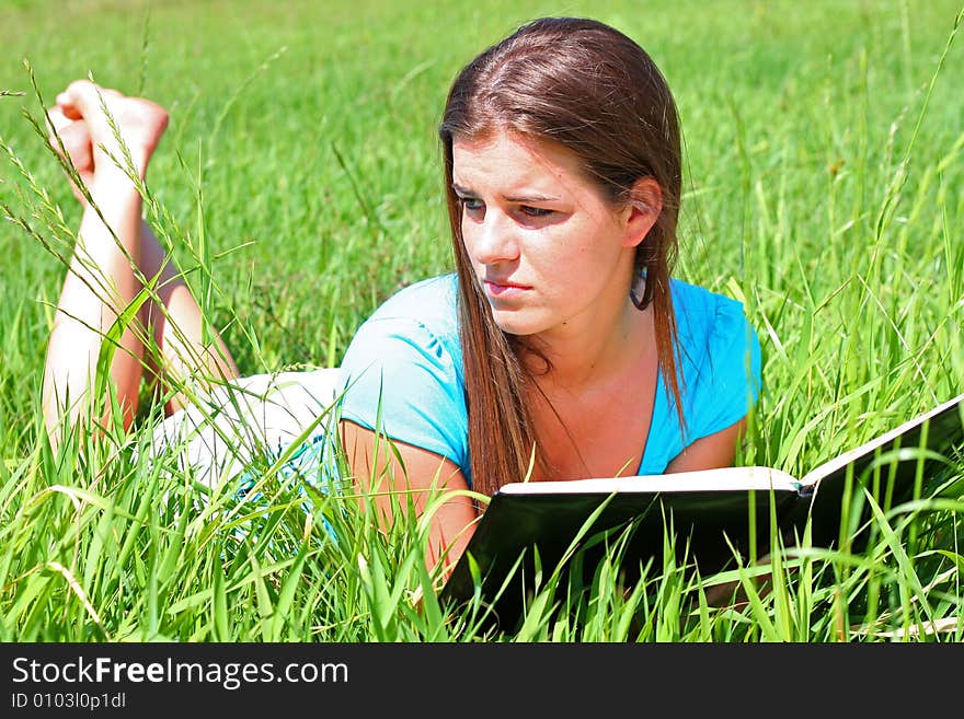 Young woman on the meadow in the summer reading a book. Young woman on the meadow in the summer reading a book.