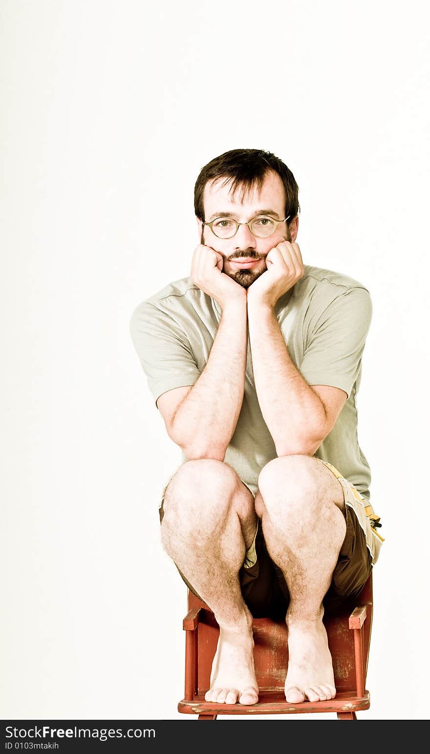 A man in his mid thirties, sitting on a feeding chair.