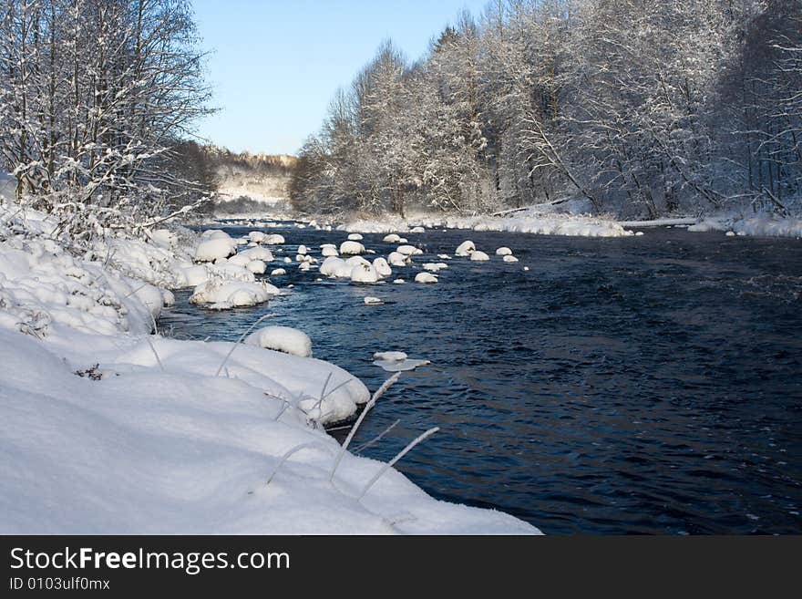 Winter landscape with the river, the blue sky and clouds