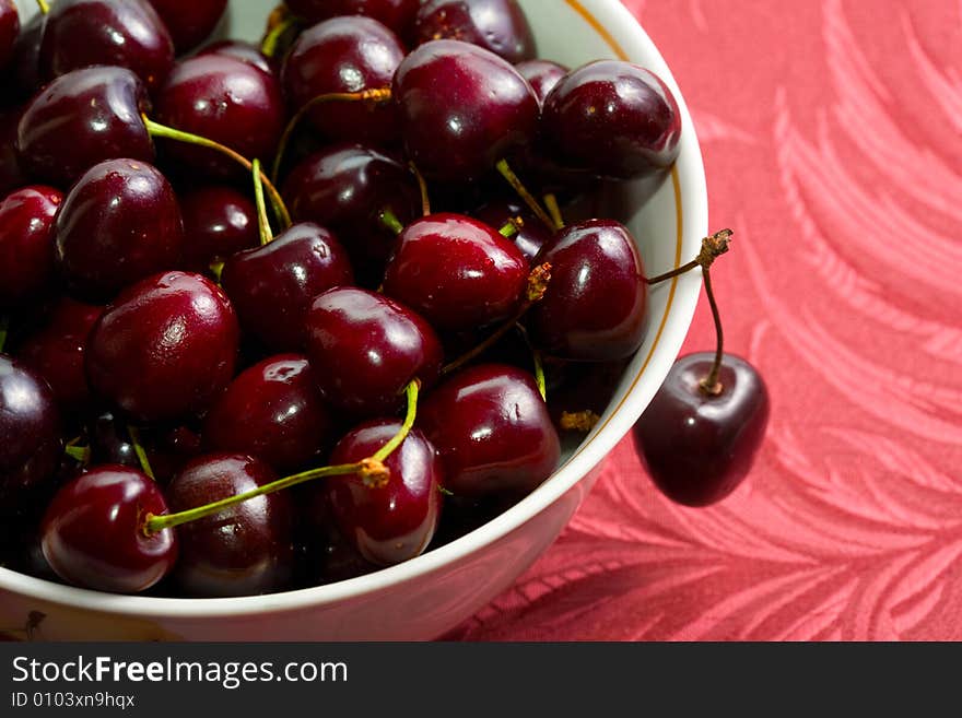 Ripe sweet cherry in a plate on a red napkin