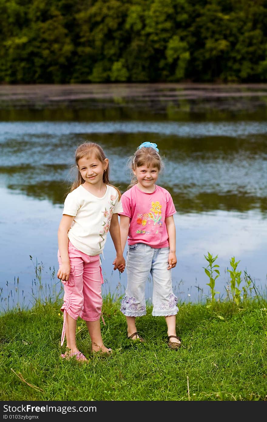 Two little girls on a bank of a river