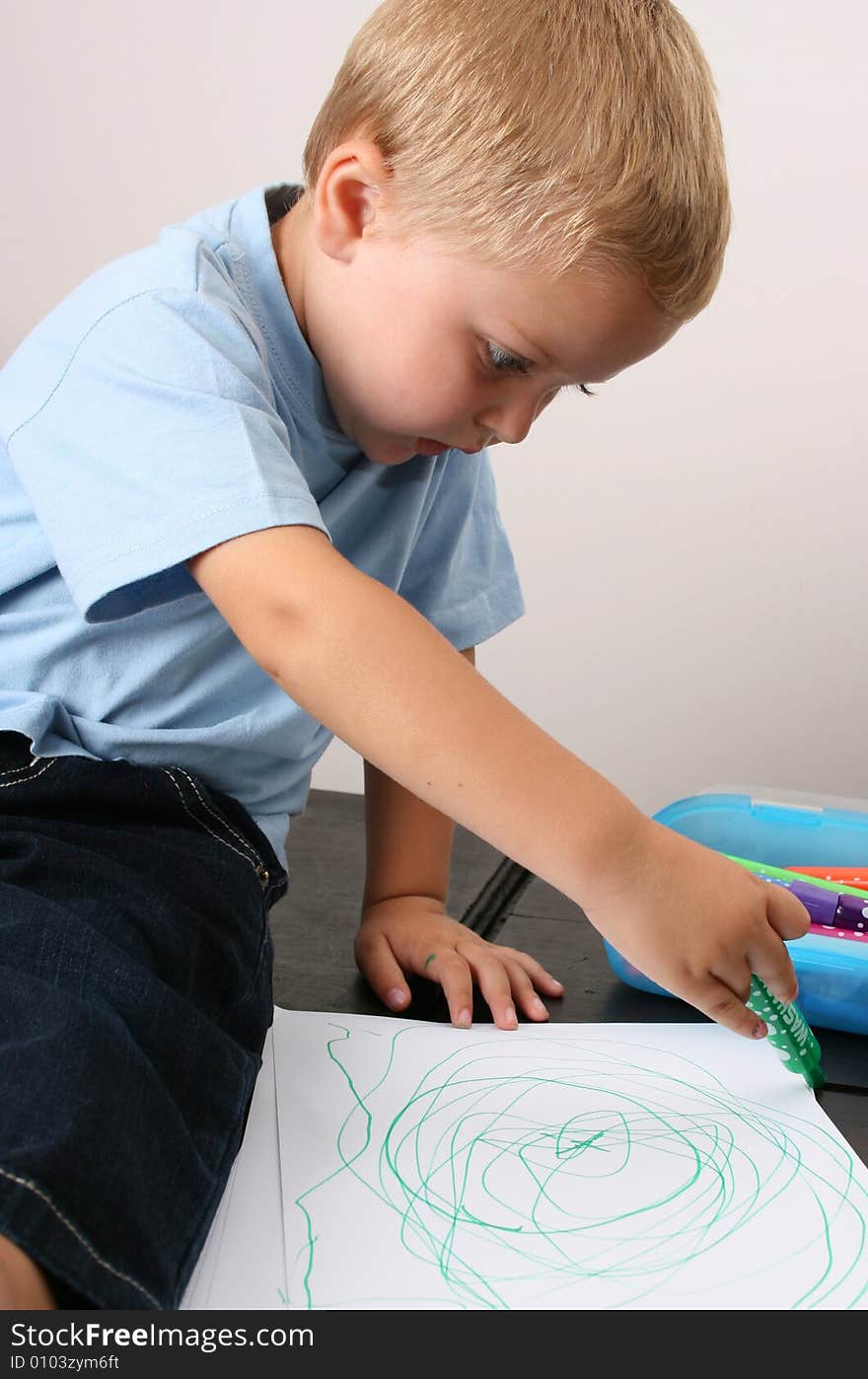 Toddler drawing on a white sheet with a green pen