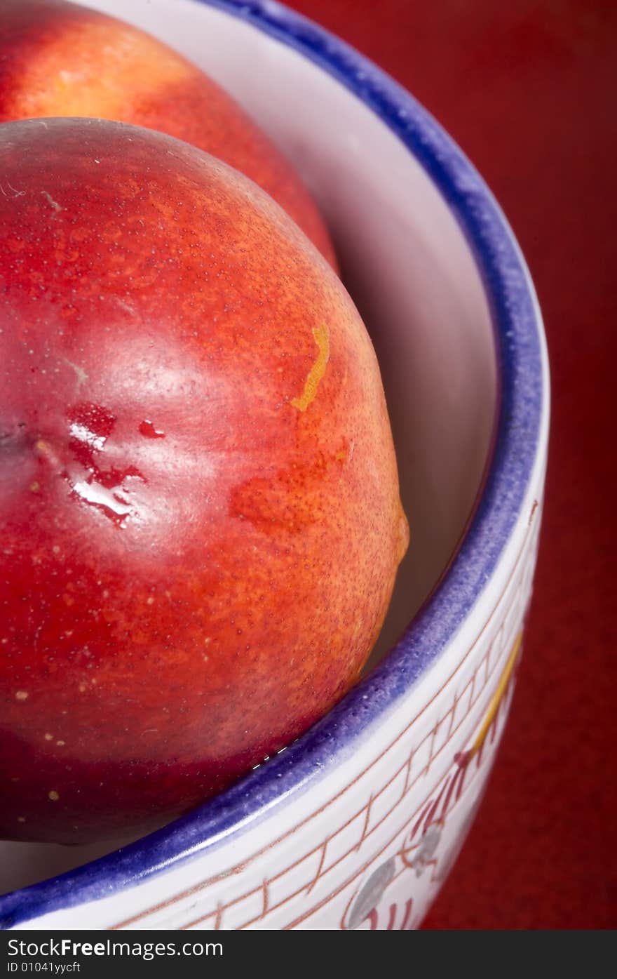 Fresh peaches in bowl on red background