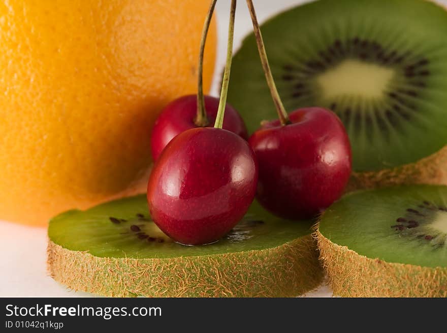 Cherry, orange and kiwi on the white background. Cherry, orange and kiwi on the white background