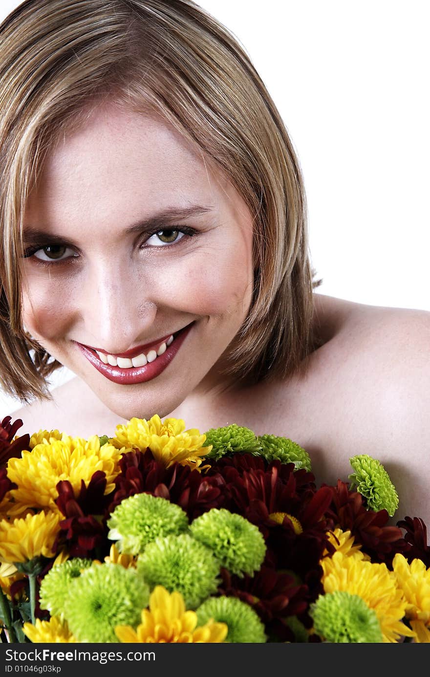 Beautiful blonde woman with bright makeup smiling from behind a bunch of colorful flowers