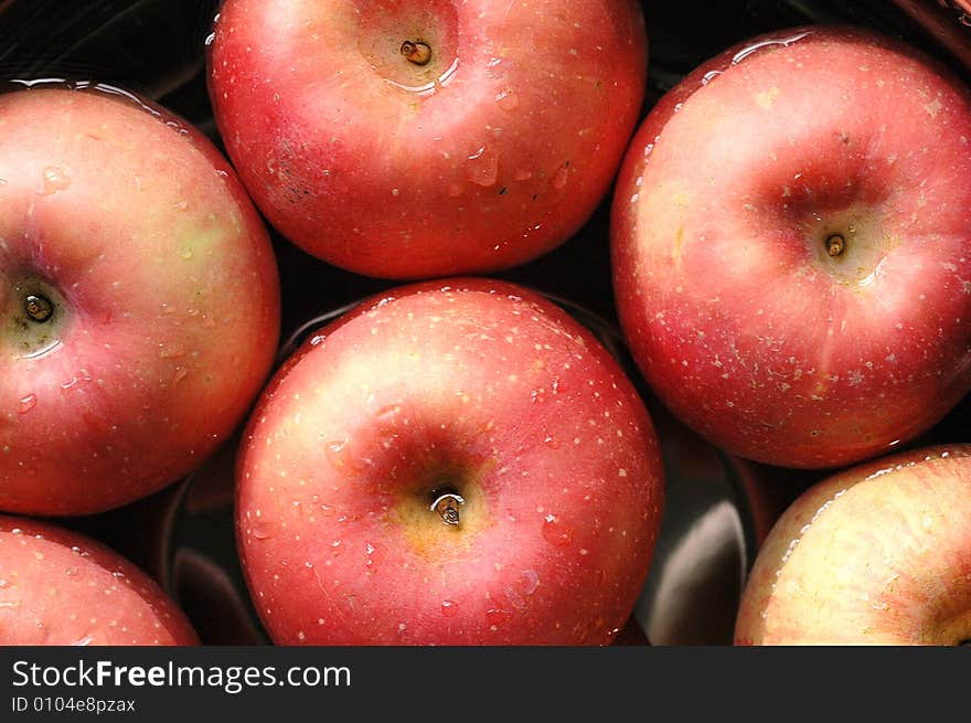 Fresh red apples floating on water in container